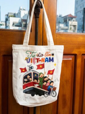 Túi Tote Canvas In Hình Việt Nam Không chỉ đơn thuần là một chiếc túi thời trang, túi tote canvas in hình Việt Nam còn mang đến những giá trị tinh thần đặc biệt. Hình ảnh lá cờ đỏ sao vàng cùng các nhân vật vui tươi trên nền túi tạo nên cảm giác gần gũi, thân thiện và tràn đầy năng lượng tích cực. Trong bối cảnh giới trẻ ngày càng quan tâm đến việc thể hiện cá tính thông qua phụ kiện thời trang, những sản phẩm mang đậm dấu ấn văn hóa Việt Nam đang trở thành xu hướng được yêu thích. Chiếc túi tote này chính là sự kết hợp hoàn hảo giữa thời trang hiện đại và niềm tự hào dân tộc. Thiết Kế Tối Giản Nhưng Vô Cùng Nổi Bật Điểm đặc biệt của sản phẩm nằm ở khả năng thu hút ánh nhìn ngay từ lần đầu tiên. Nền vải canvas màu kem thanh lịch giúp làm nổi bật các họa tiết in nhiều màu sắc. Hình ảnh đoàn tàu, lá cờ Việt Nam cùng những nhân vật hoạt hình đáng yêu tạo nên tổng thể sinh động nhưng không rối mắt. Thiết kế này phù hợp với nhiều độ tuổi khác nhau và có thể sử dụng trong nhiều môi trường từ trường học, văn phòng cho đến các buổi dạo phố cuối tuần. Không Gian Lưu Trữ Lý Tưởng Nhiều người lựa chọn túi tote bởi sự tiện lợi mà sản phẩm mang lại. Với thiết kế lòng túi rộng rãi, người dùng có thể dễ dàng mang theo: Sách vở học tập. Tài liệu làm việc. Máy tính bảng. Bình nước cá nhân. Mỹ phẩm. Ví tiền. Điện thoại. Ô gấp gọn. Tai nghe và phụ kiện cá nhân. Sức chứa lớn giúp chiếc túi đáp ứng hiệu quả nhu cầu sử dụng mỗi ngày mà vẫn đảm bảo tính thẩm mỹ. Phụ Kiện Thời Trang Dành Cho Người Yêu Văn Hóa Việt Ngày càng có nhiều bạn trẻ yêu thích các sản phẩm mang đậm bản sắc dân tộc. Túi tote canvas in hình Việt Nam không chỉ giúp hoàn thiện phong cách thời trang mà còn là cách thể hiện tình yêu quê hương theo phong cách hiện đại. Hình ảnh được thiết kế trẻ trung, sáng tạo nên phù hợp với xu hướng thẩm mỹ của thế hệ trẻ hiện nay. Đây cũng là sản phẩm được nhiều du khách lựa chọn làm quà lưu niệm sau những chuyến tham quan tại Việt Nam. Dễ Dàng Mang Theo Trong Mọi Hành Trình Một ưu điểm nổi bật khác của túi tote canvas là trọng lượng nhẹ. Người dùng có thể: Gấp gọn trong vali du lịch. Mang theo khi mua sắm. Sử dụng làm túi dự phòng. Đem theo trong các chuyến dã ngoại. Sử dụng hằng ngày mà không gây cảm giác nặng nề. Sự tiện lợi này giúp sản phẩm trở thành người bạn đồng hành lý tưởng trong cuộc sống hiện đại. Xu Hướng Sử Dụng Túi Tote Thân Thiện Với Môi Trường Bên cạnh yếu tố thời trang, nhiều người lựa chọn túi tote canvas vì tính thân thiện với môi trường. Sản phẩm có thể tái sử dụng nhiều lần, góp phần: Giảm sử dụng túi nilon. Hạn chế rác thải nhựa. Xây dựng lối sống xanh. Nâng cao ý thức bảo vệ môi trường. Đây là xu hướng tiêu dùng tích cực đang được cộng đồng trẻ hưởng ứng mạnh mẽ. Món Quà Lưu Niệm Đầy Ý Nghĩa Nếu bạn đang tìm kiếm một món quà mang đậm dấu ấn Việt Nam thì chiếc túi tote này là lựa chọn rất phù hợp. Sản phẩm thích hợp làm quà tặng cho: Bạn bè. Học sinh. Sinh viên. Người thân. Du khách quốc tế. Đối tác trong các sự kiện văn hóa. Không chỉ hữu ích trong cuộc sống hằng ngày, chiếc túi còn mang giá trị tinh thần và thông điệp tích cực về tình yêu quê hương đất nước. Sản Phẩm Đáng Có Trong Tủ Đồ Của Mỗi Người Với thiết kế đẹp mắt, chất liệu bền bỉ và ý nghĩa đặc biệt, túi tote canvas in hình Việt Nam xứng đáng trở thành phụ kiện không thể thiếu trong tủ đồ của mỗi người. Đây là sản phẩm vừa giúp bạn thể hiện phong cách cá nhân, vừa lan tỏa những giá trị văn hóa Việt Nam một cách gần gũi và sáng tạo.
